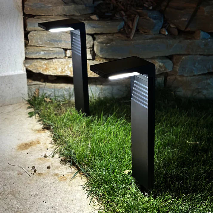 Svart trädgårdslampa monterad vid stenmur