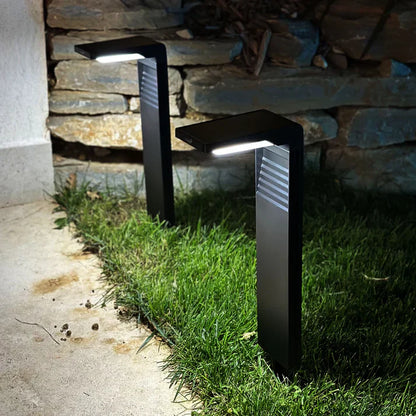 Svart trädgårdslampa monterad vid stenmur