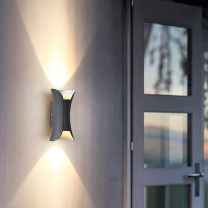 Närbild på vit och guld vägglampa på vägg